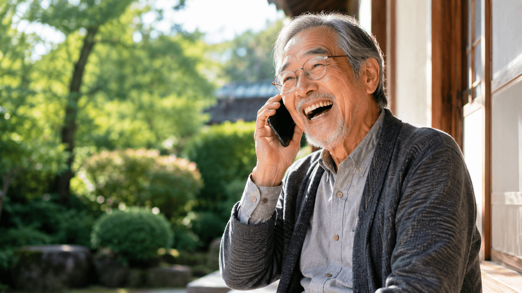 70代の男性が縁側に座って電話しながら笑顔で話している